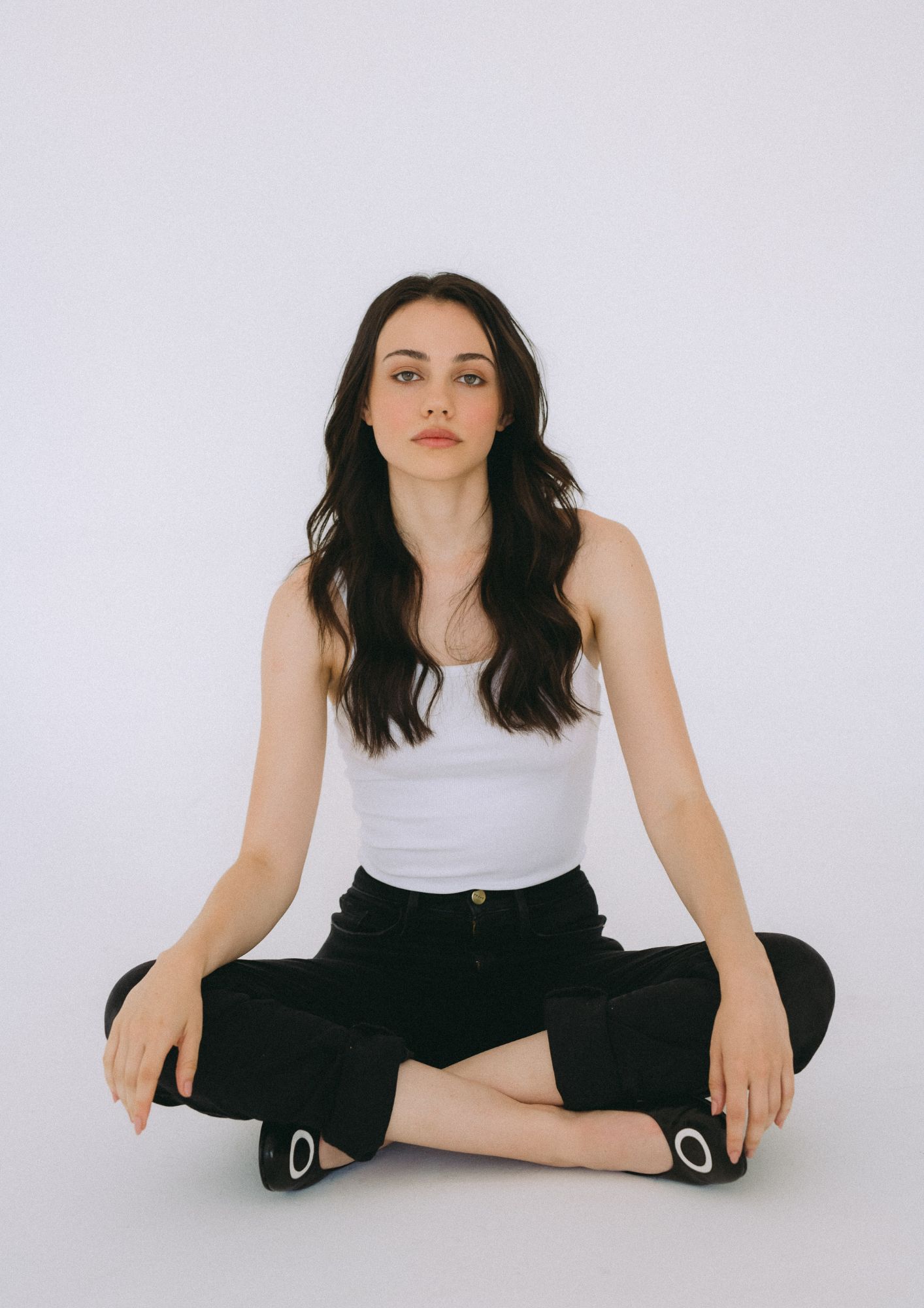 Portrait of Emilia Grillasca, seated cross-legged against a pale backdrop.